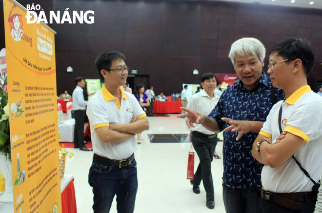 Anh Trầm Nguyên Thành (ngoài cùng bên trái) và anh Bùi Như Mậu (ngoài cùng bên phải) trao đổi với các đại biểu tham quan gian hàng tại hội nghị Khoa học và Công nghệ vùng Nam Trung Bộ và Tây Nguyên.