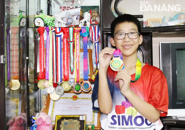 Thanh is seen showing off his Maths medals he has won over the past years