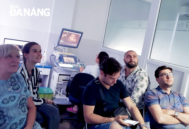 Relatives of a pregnant woman are seen watching fetal ultrasound images