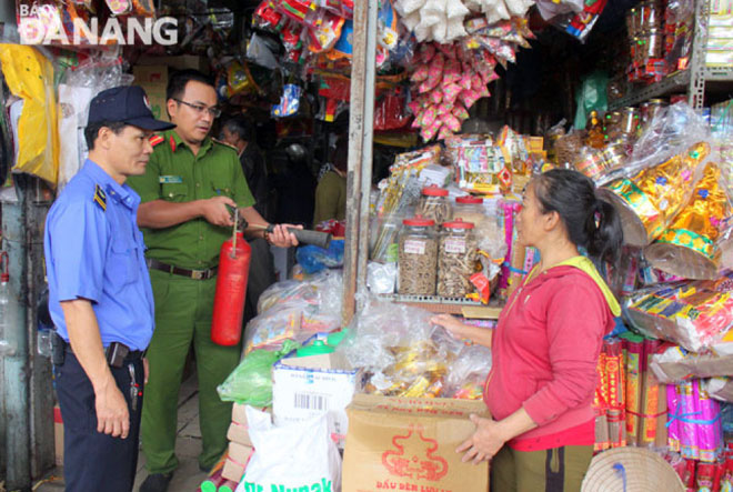 Công an phường Hải Châu 2 (quận Hải Châu) và bảo vệ chợ Cồn hướng dẫn tiểu thương sử dụng bình chữa cháy xách tay. 