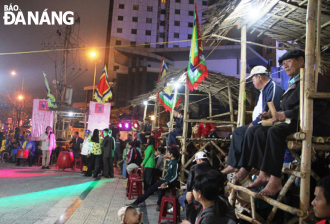 Local residents and visitors enjoying ‘bai choi’ performance on the pavement of Tran Hung Dao at the eastern end of the Rong (Dragon) Bridge 