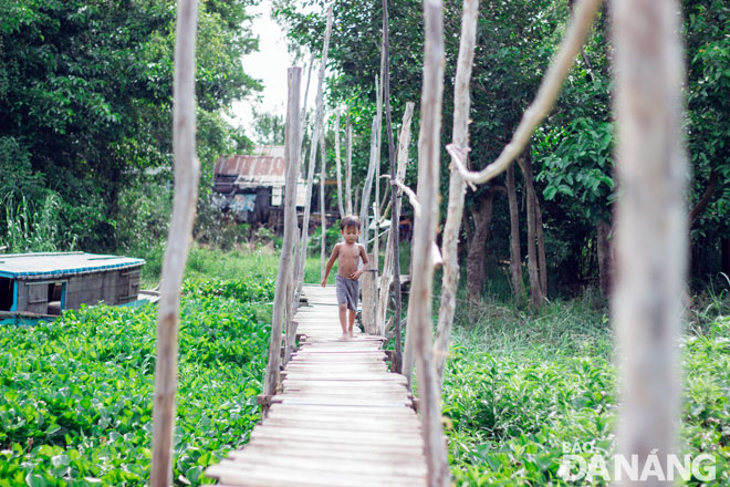 Người dân ở làng nổi đi từ sông lên đất liền bằng những chiếc cầu gỗ, cứ mỗi mùa nước lên, mặt cầu lại được treo lên cao theo con nước.