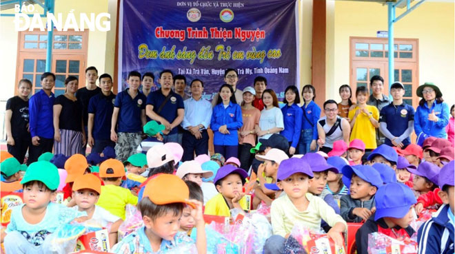 Các sinh viên, thanh niên tình nguyện Đà Nẵng trao quà cho trẻ em, người dân thôn Nóc Ông Vũ (Ảnh do CLB Từ thiện và Bảo vệ quyền trẻ em Hương Lam cung cấp).