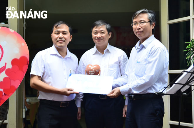 Deputy Director of VNPT Da Nang Nguyen Nho Tuy (right) giving donations to Chairman of the municipal Journalists' Association Nguyen Duc Nam (left) under the witness of Vice Chairman Dung