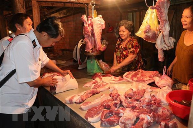 Lực lượng chức năng kiểm tra buôn bán thịt lợn tại các chợ xã. (Ảnh: Huỳnh Phúc Hậu/TTXVN)