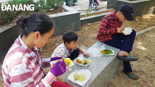 Ba mẹ con chị Thúy ăn vội bữa trưa tại công viên Thanh Bình sau buổi bán vé số.     