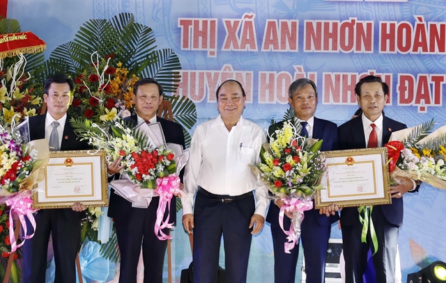 Prime Minister Nguyen Xuan Phuc (centre) hands over certificates of merit to representatives of An Nhon and Hoai Nhon districts in the central coastal province of Binh Dinh, which have completed the construction of new rural areas. This is part of his working visit to the province to host the economic conference on Tuesday.