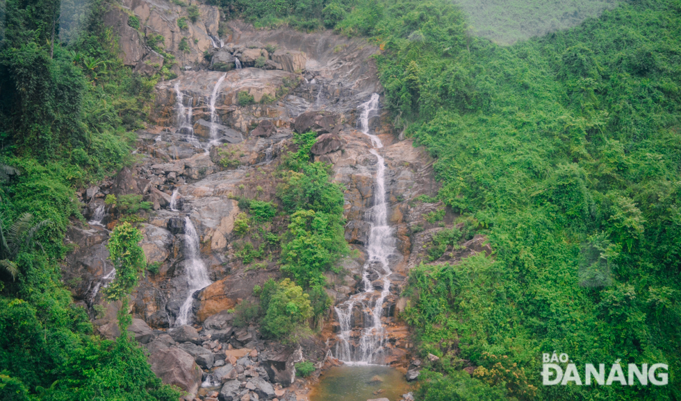   A waterfall, surrounded by lush trees and primeval rocks in Hoa Son Commune, creating massive clouds of eye-catching white foam