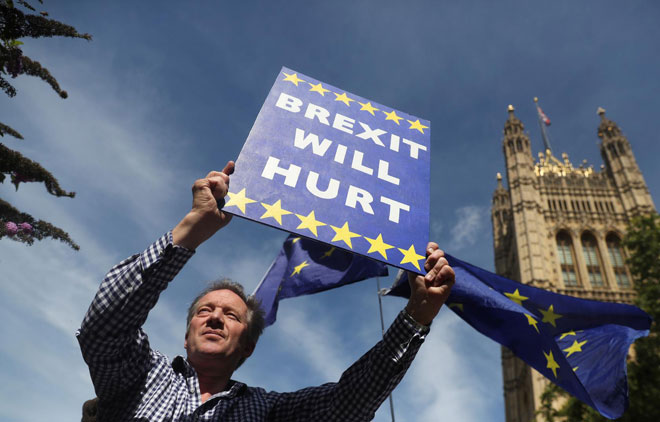 Một người biểu tình có mặt bên ngoài tòa nhà Quốc hội ở London mang tấm biển có dòng chữ “Brexit sẽ gây tổn hại”. 		Ảnh: Reuters