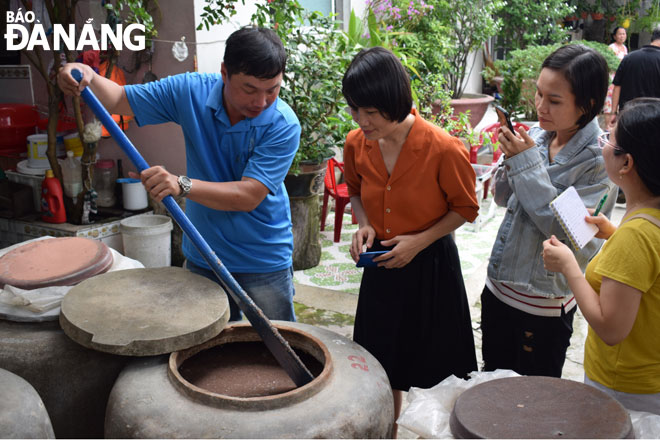 Người dân làng nghề nước mắm Nam Ô giới thiệu về phương pháp làm mắm theo công thức gia truyền “ 3 cá 1 muối”.  Ảnh: KHÁNH HÒA