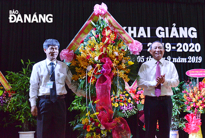 Secretary Nghia (right) presenting a wreath of flowers to a representative of the Le Quy Don Senior High School for Gifted Pupils