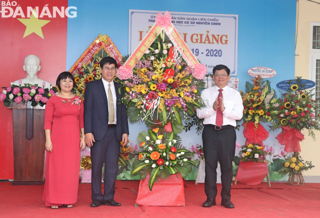 Deputy Secretary Tri (right) giving a wreath of flowers to congratulate teachers and pupils of the Nguyen Chon Junior High School on the special occasion