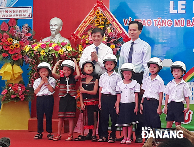 Vice Chairman Dung (left) and a leader of the municipal Youth Union presenting helmets to Hoa Bac primary school pupils