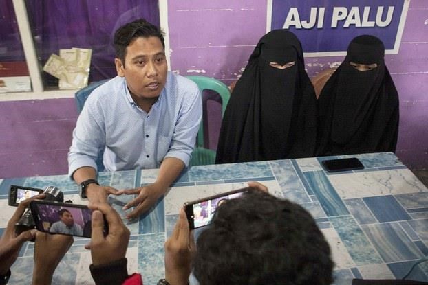 Andi Akbar (left), a lawyer from a group called the Muslim Legal Team, sits with the wives of suspected militants Mohamad Arkam and Adi Saputra during a news conference in Palu, Indonesia, on Sept. 4.  (Photo: Bernama)