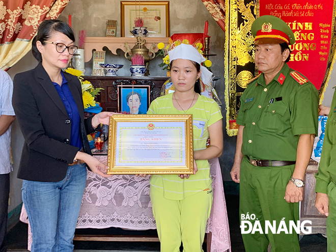 Bà Trần Thị Thanh Tâm trao bằng khen của Chủ tịch UBND thành phố truy tặng cho anh Trần Long Khải. Ảnh: ST