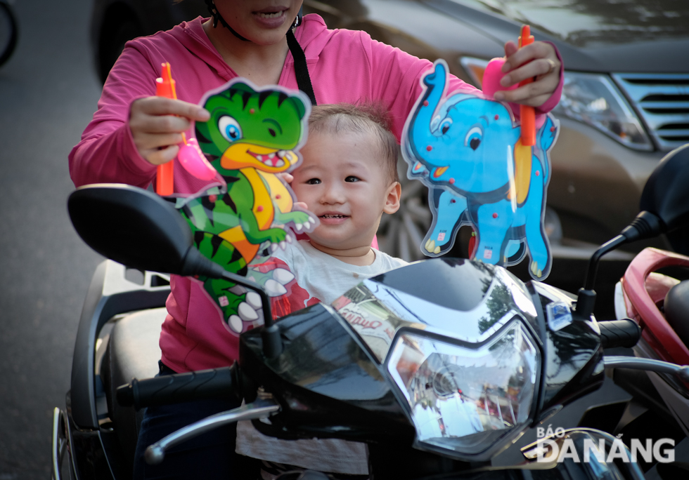 A kid expressing his joy as his mother buys animal-shaped plastic lanterns to him