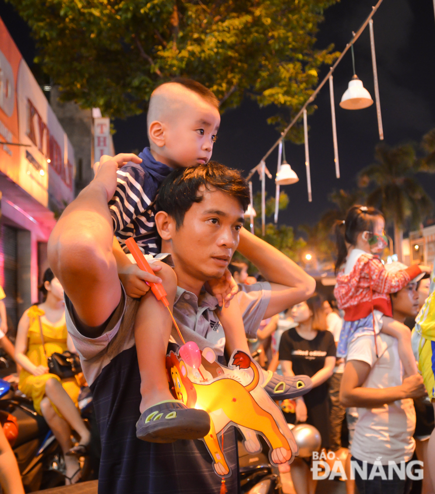 A father holding a kid on his back to watch lion dance performances