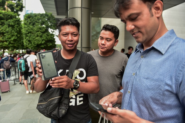 Một người dân bản xứ (Singapore) hân hoan với chiếc điện thoại mới trên tay, thành quả sau một ngày dài xếp hàng.