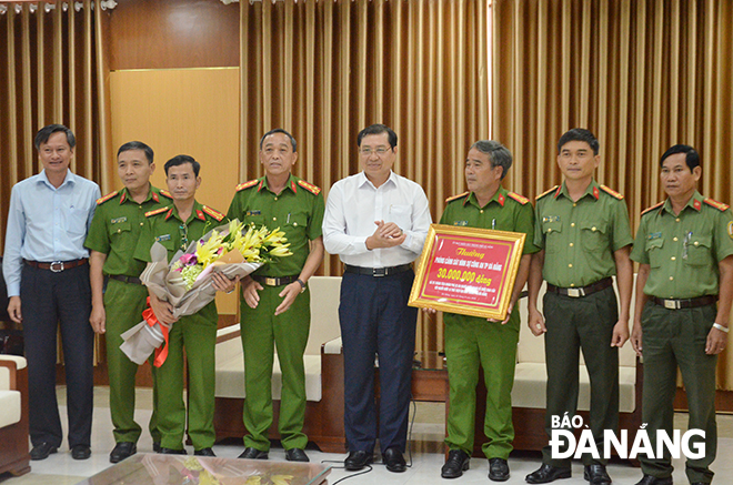  Municipal People’s Committee Chairman Huynh Duc Tho ( 4th , right) presenting the reward to representatives from the Criminal Investigation Division