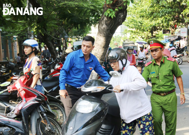 Đoàn viên thanh niên phường Thọ Quang và Công an phường hướng dẫn phụ huynh để xe đúng nơi quy định trước cổng trường. Ảnh: THANH TÌNH 