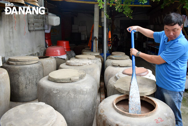 Doanh nhân Bùi Thanh Phú bên sản phẩm nước mắm mang hồn cốt của làng nghề làm mắm truyền thống Nam Ô.