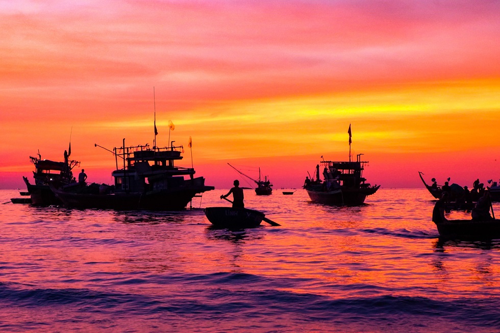 Fishing vessels returning the shore at sunrise 