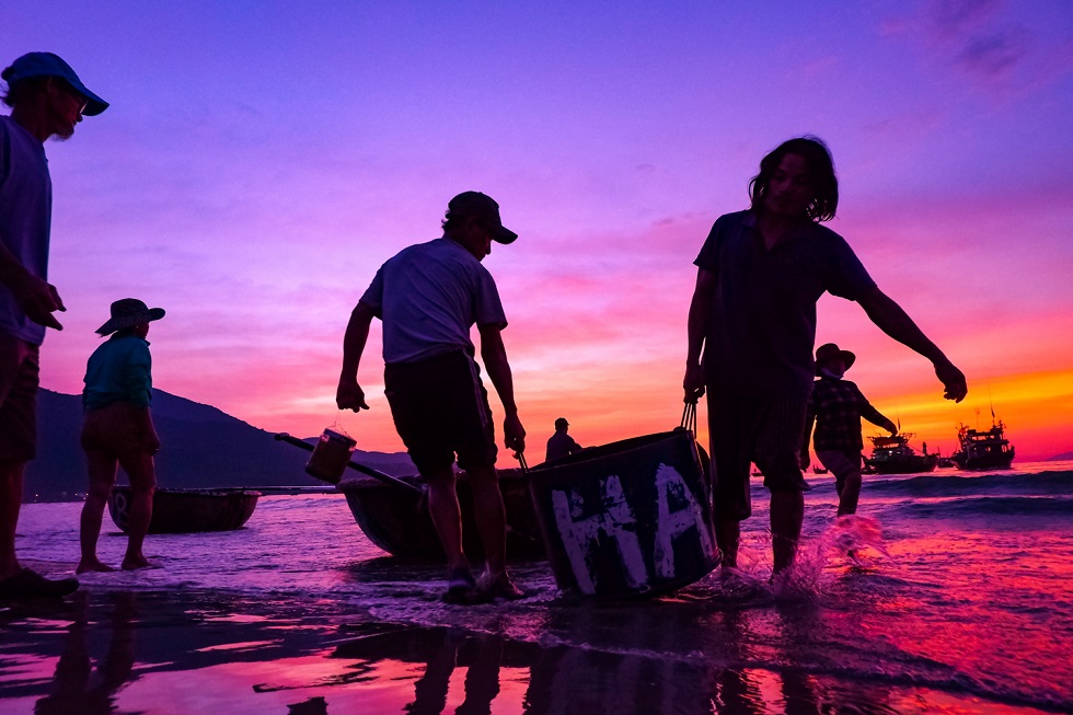 Fishermen bringing ashore baskets full of fish