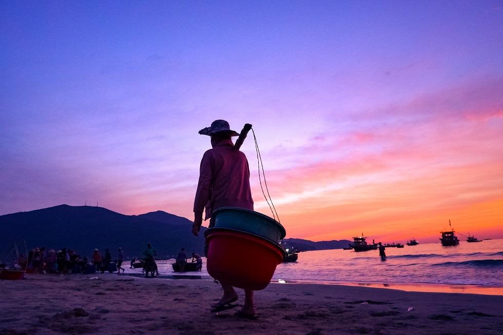 A woman with bamboo frame over her shoulders is in a hurry to go to an early-morning fish market