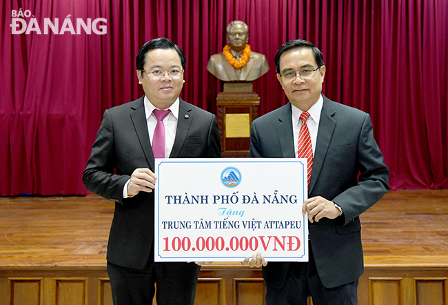 Municipal People's Council Vice Chairman Le Minh Trung (left) giving 100 million VND to the Attapeu Province -based Vietnamese language centre