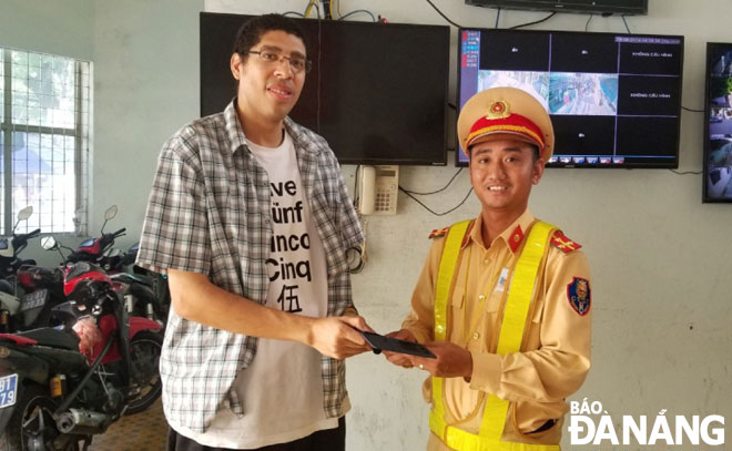 Mr Alberto (left) receiving his lost property from a police officer