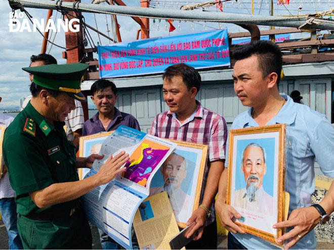 Trung tá Văn Đức Trường, Chính trị viên Đồn Biên phòng Sơn Trà tặng ảnh Bác Hồ và tuyên truyền, hướng dẫn cho ngư dân một số quy định khi ra khơi đánh bắt trên biển.