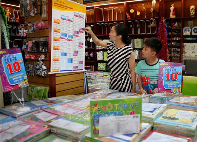 Phụ huynh xem bảng giá niêm yết sách giáo khoa tại cửa hàng thuộc hệ thống phân phối chính thức của NXB Giáo dục Việt Nam. Ảnh: TTXVN