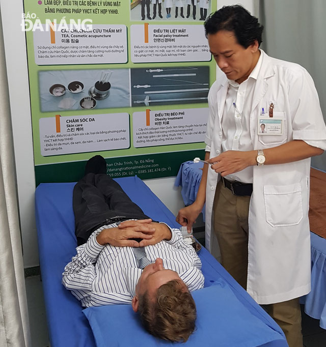 Herb doctor Nguyen Van Dung examining a foreign patient at the 2nd facility of the Traditional Medicine Hospital