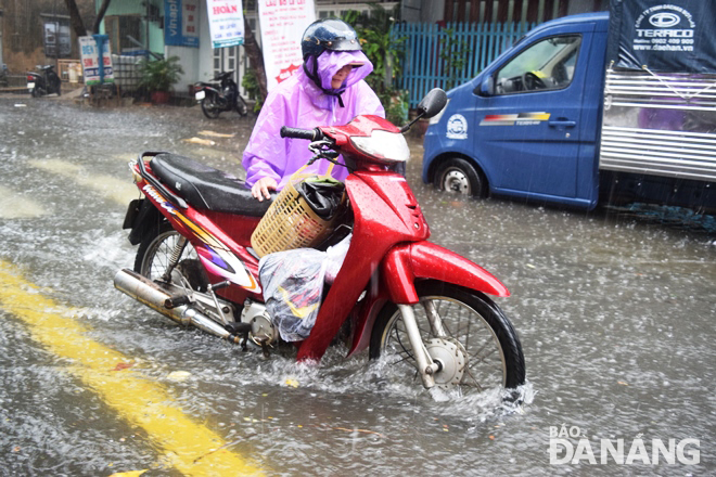 Road users pushing their vehicles through an inundated street