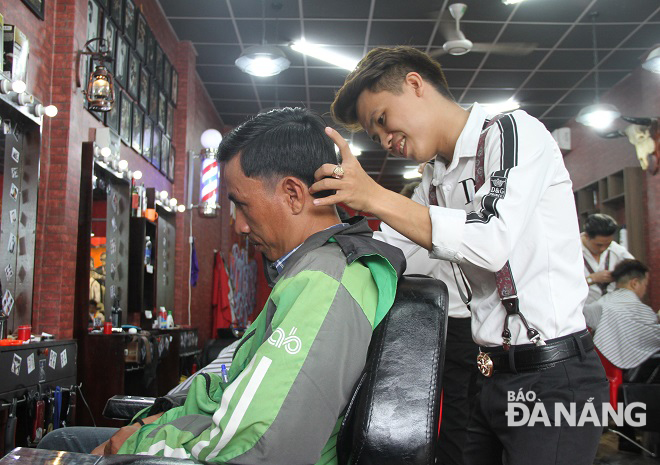 Mr Vuong (right) giving free haircut to a Grab Bike driver 