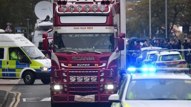  Police officers escort the lorry in which 39 dead bodies were discovered. — AFP Photo Read more at http://vietnamnews.vn/society/537520/vietnamese-agencies-support-families-of-potential-lorry-victims.html#RkXtRC5e6SQJajj3.99