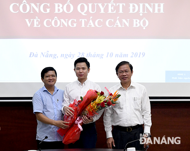 Chủ tịch HĐND thành phố Nguyễn Nho Trung (bìa trái) và Trưởng ban Tổ chức Thành ủy Võ Văn Thương (bìa phải) trao quyết định và tặng hoa chúc mừng ông Đoàn Xuân Hiếu. Ảnh: ĐẶNG NỞ
