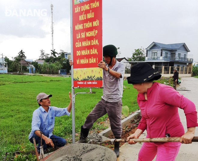 Người dân thôn Lệ Sơn Bắc, xã Hòa Tiến gia cố hệ thống khẩu hiệu trên tuyến đường nông thôn mới kiểu mẫu.