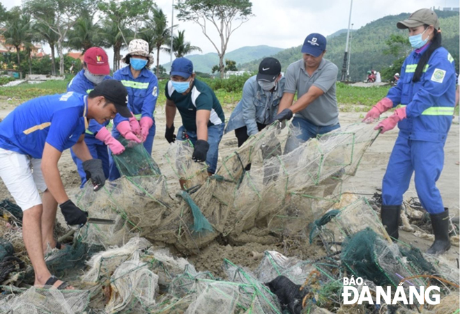 Employees from the Da Nang Urban Environment Joint Stock Company and the Management Board of the Son Tra Peninsula and Da Nang Tourism Beaches cleaning up litter-strewn Tho Quang Beach caused by the recent storm.