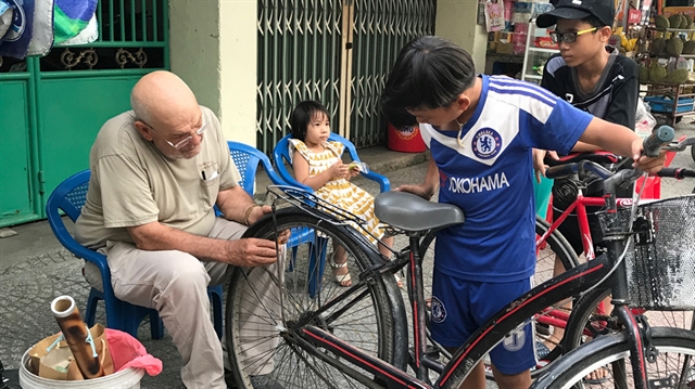 David Clark is seen sticking reflective tapes onto the bicycles of a passer-by in Da Nang. — Photo cadn.com.vn