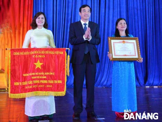Thừa ủy quyền Thủ tướng Chính phủ, Phó Chủ tịch UBND thành phố Lê Trung Chinh (giữa) trao Cờ thi đua và Bằng khen của Chính phủ cho hai tập thể trường học. Ảnh: NGỌC PHÚ