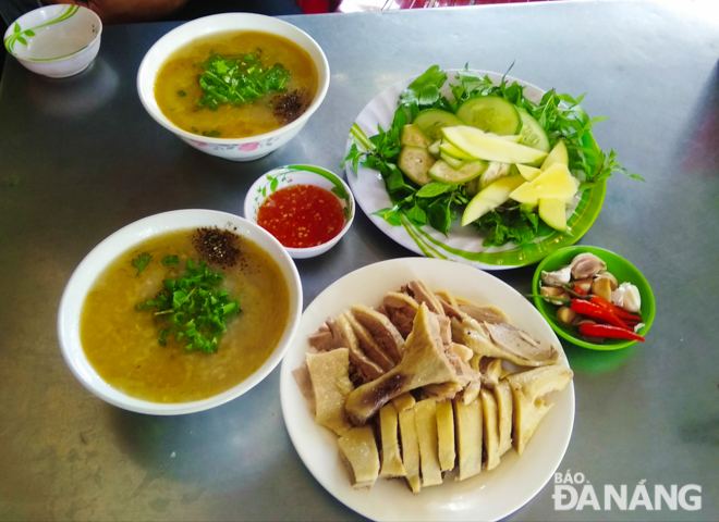 A bowl of hot tasty porridge besides a mouth-watering plate of duck meat and fresh raw vegetables