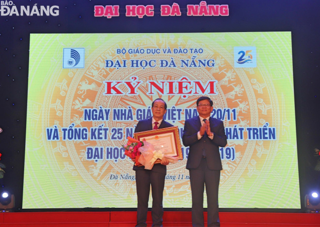  Municipal Party Committee Deputy Secretary Vo Cong Tri (right) awarding the second-class labour medal of the President to Assoc.Prof.Dr.  Phan Van Hoa, the former Rector of the University of Foreign Languages and Studies, a member of UDN 