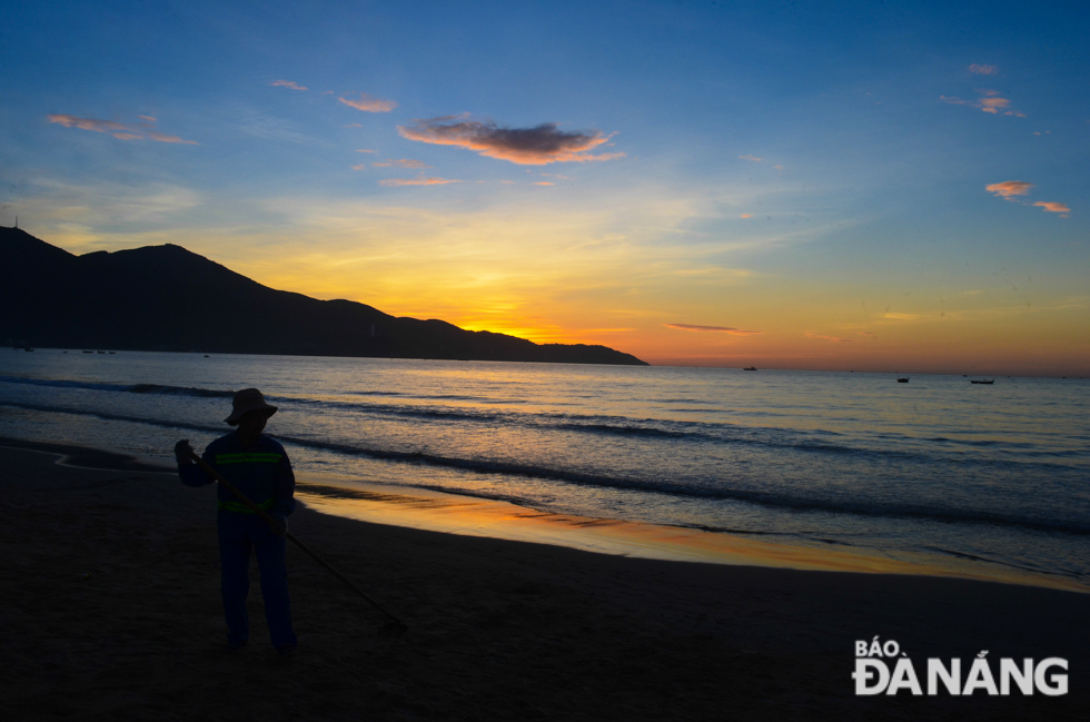 A cleaner from the Song Bien Environmental Service doing his job at a beach in the early morning