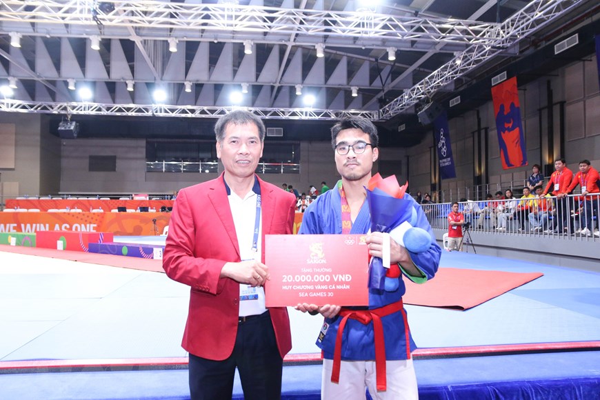 Trưởng đoàn thể thao Việt Nam Trần Đức Phấn trao thưởng cho võ sỹ Bùi Minh Quân. (Ảnh: Hoàng Linh/TTXVN)