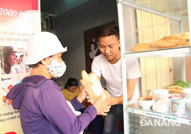 Vinh giving free a loaf of bread to a woman