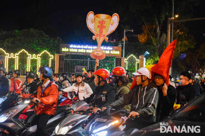 Người hâm mộ tụ tập thành từng nhóm với cờ đỏ sao vàng và kèn cổ động.