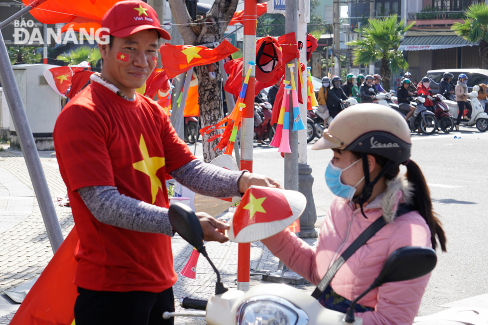 A customer buying a small conical hat with national flag on a local street to cheer for Viet Nam at the SEA Games final game on Tuesday afternoon.