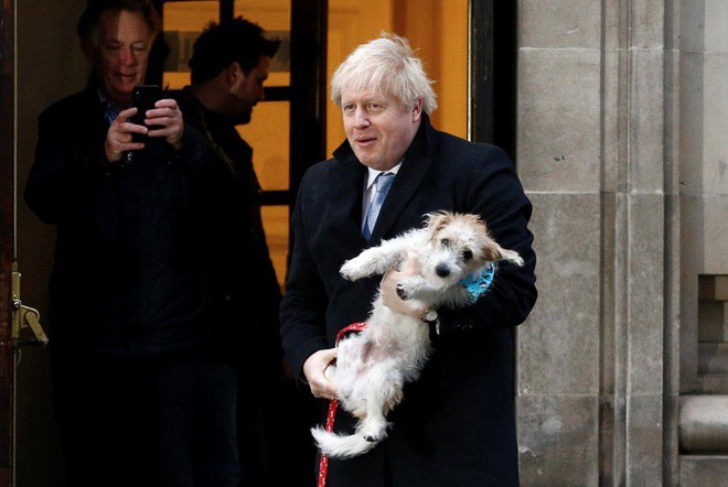 Thủ tướng Anh Boris Johnson rời phòng bỏ phiếu tại Methodist Central Hall, Westminster, với chú chó Dilyn sau khi bỏ phiếu trong cuộc tổng tuyển cử ở London, Anh, ngày 12/12. Ảnh:  Reuters