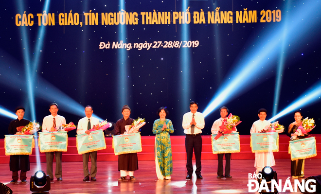 Chủ tịch Ủy ban MTTQ Việt Nam thành phố Đặng Thị Kim Liên trao cờ lưu niệm cho các tôn giáo, tín ngưỡng tham gia liên hoan văn nghệ.